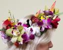 A mix of tropical flowers creates this colorful floral crown; including Cymbidium, Oncidium and Dendrobium orchids, Red anthurium and Heliconia.