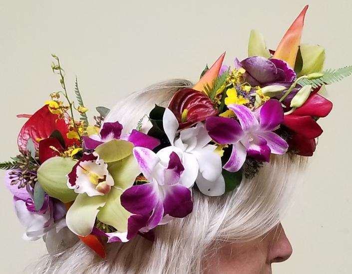 A mix of tropical flowers creates this colorful floral crown; including Cymbidium, Oncidium and Dendrobium orchids, Red anthurium and Heliconia.