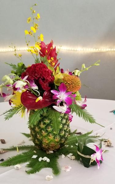 A Mutli-Colored Mix of Tropical Flowers such as Oncidium Orchids, Red Anthurium, Pincushion Protea, Purple Dendrobium Orchids, Cymbidiums orchids and Ginger all set inside a real Pineapple.