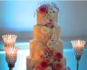 Gorgeously lit and cascading with beautiful roses and hydrangeas in shades of pink and whites, accented with jewels; this cake display steals the spotlight.