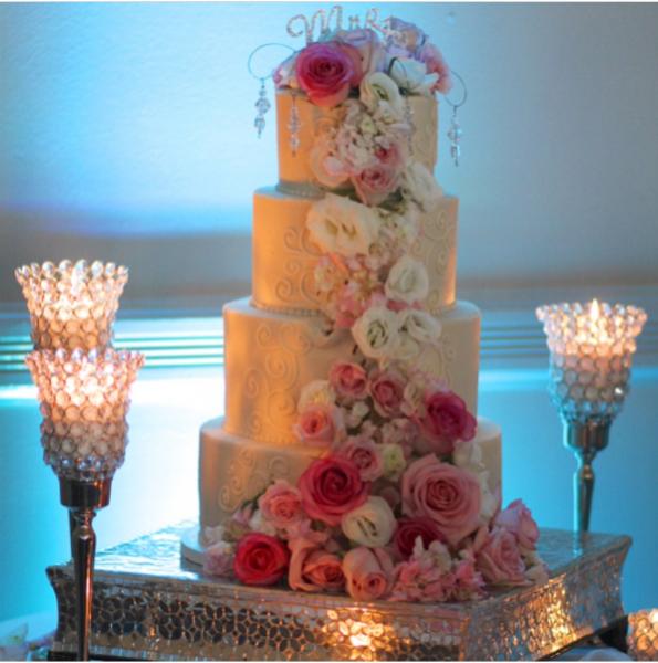 Gorgeously lit and cascading with beautiful roses and hydrangeas in shades of pink and whites, accented with jewels; this cake display steals the spotlight.