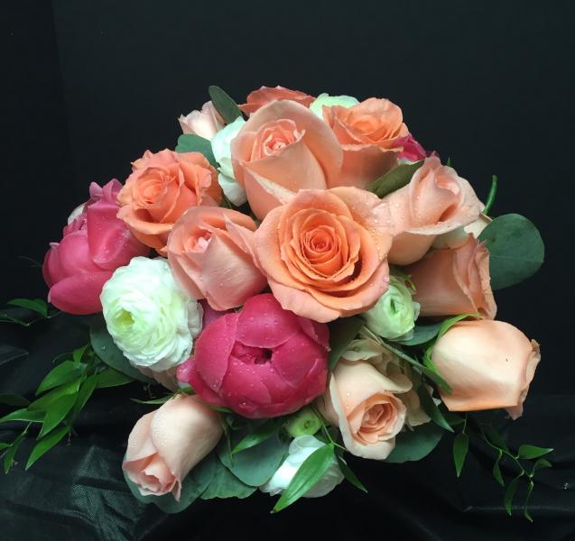 Hot pink Peonies, orange roses and white ranunculus give this bridal bouquet a tropical feel.