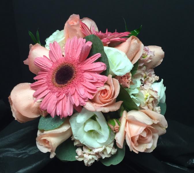 Hot pink Peonies, orange roses, and white ranunculus give this bridal bouquet a tropical feel.